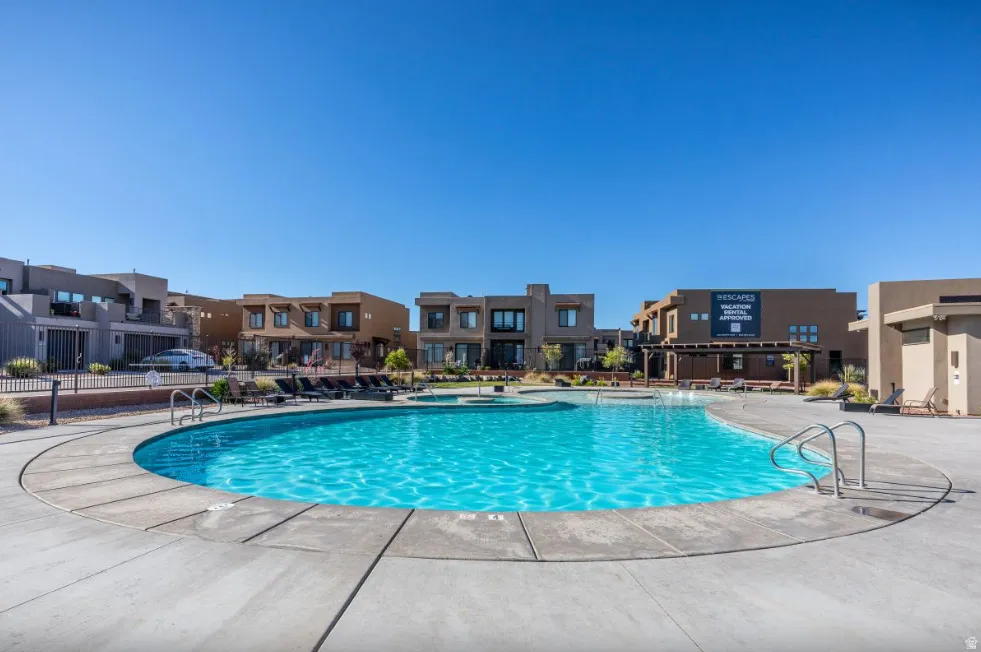 Resort-style swimming pool with integrated spa, surrounded by a concrete deck and a range of outdoor seating