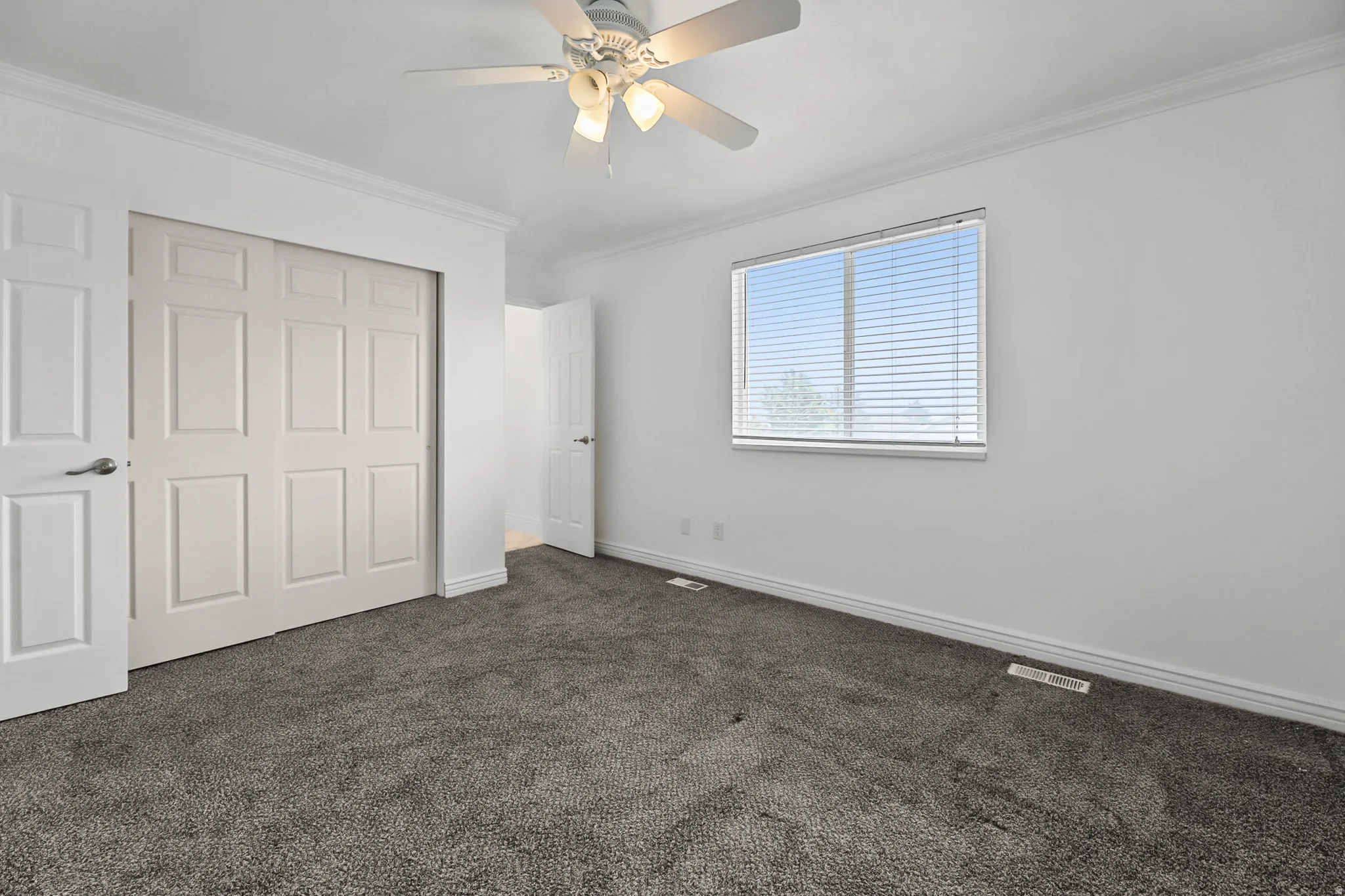 Room featuring gray carpet, white walls, and a ceiling fan with integrated lighting