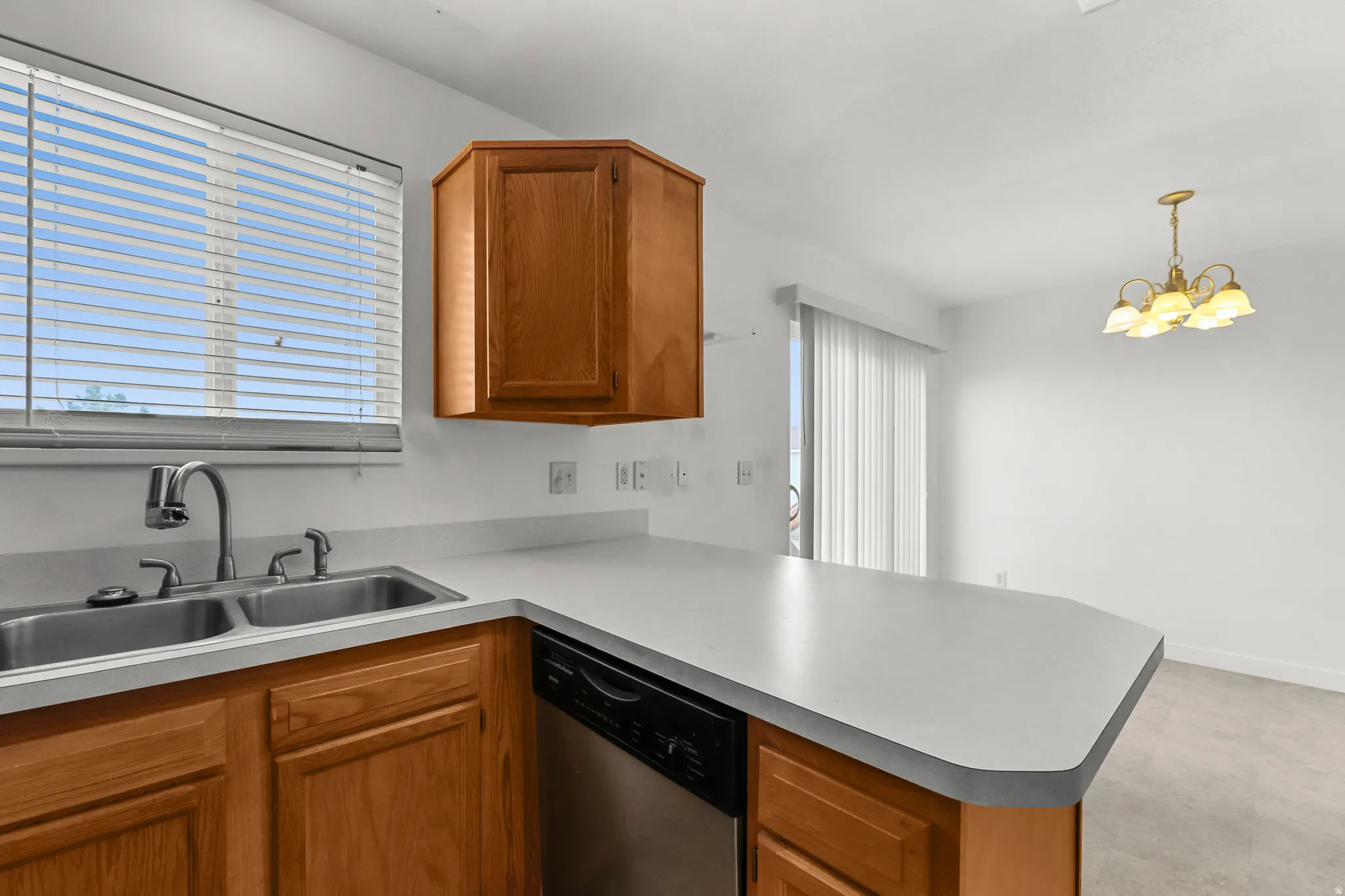 Kitchen featuring light wood-finish cabinetry, a double basin stainless steel sink, and light-toned countertops