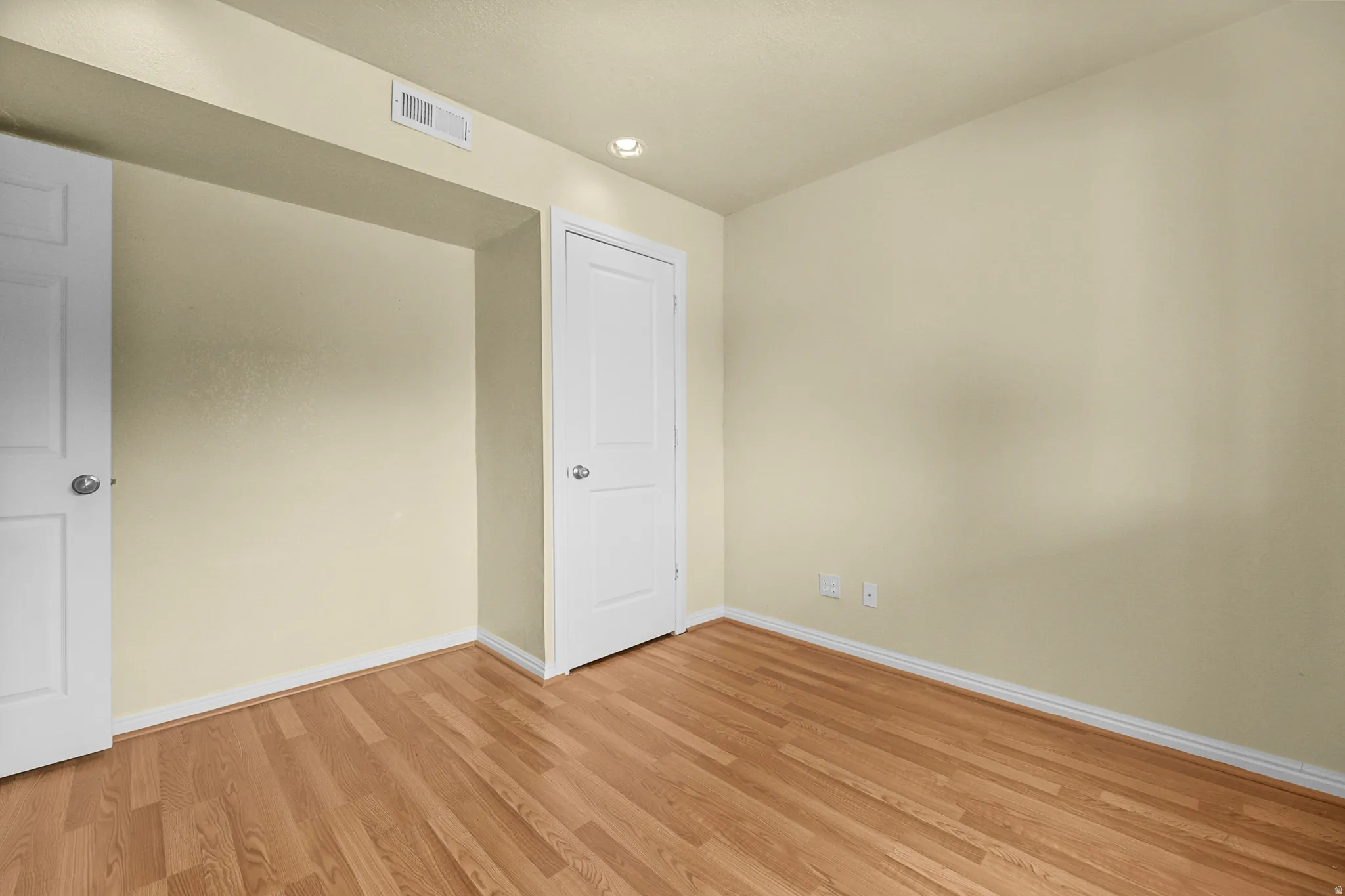 Room featuring wood-finish flooring, light-colored walls, recessed ceiling lighting, and white baseboards