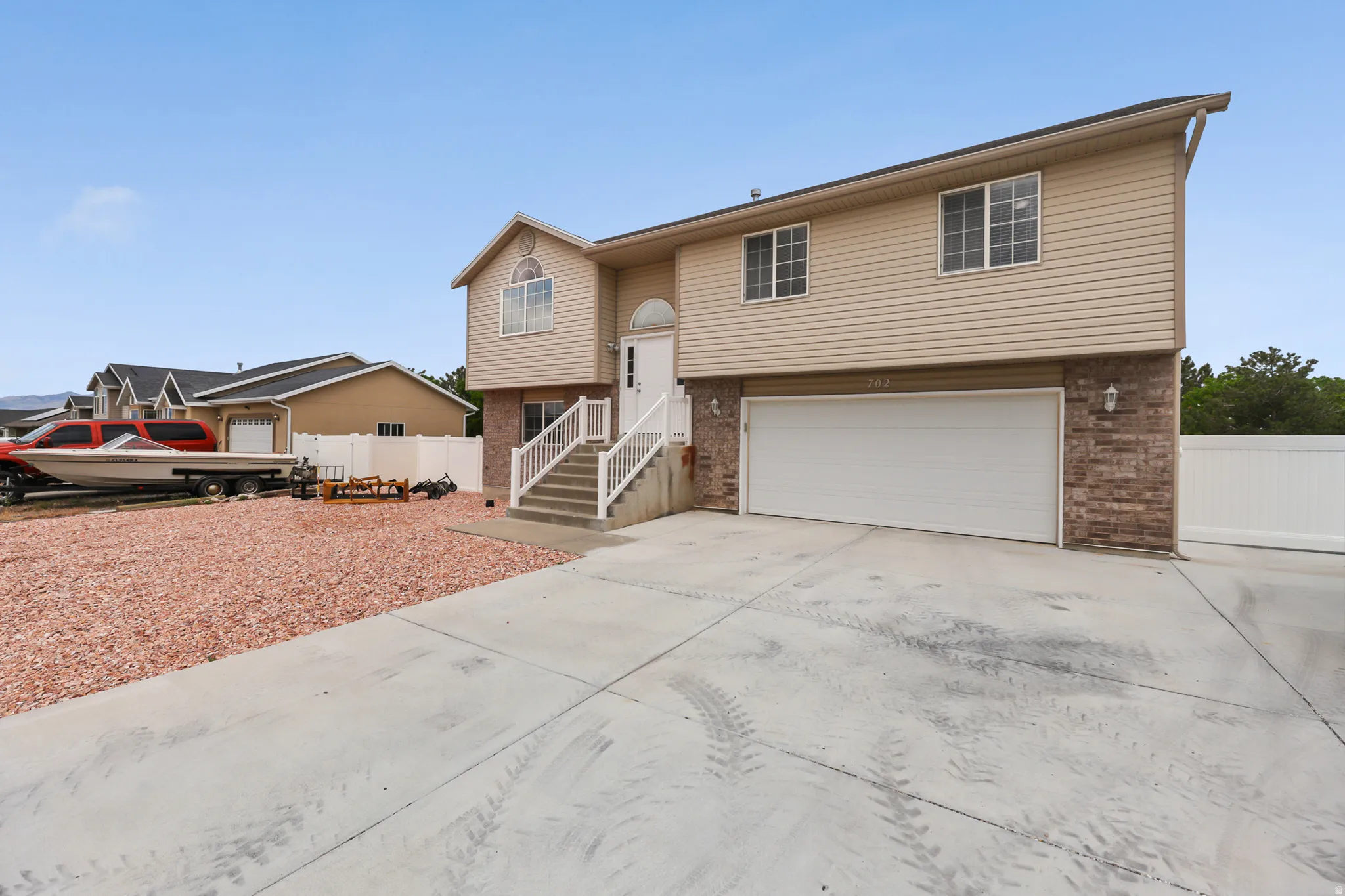 Split-level residence featuring a two-car garage, brick and siding exterior, and a concrete driveway