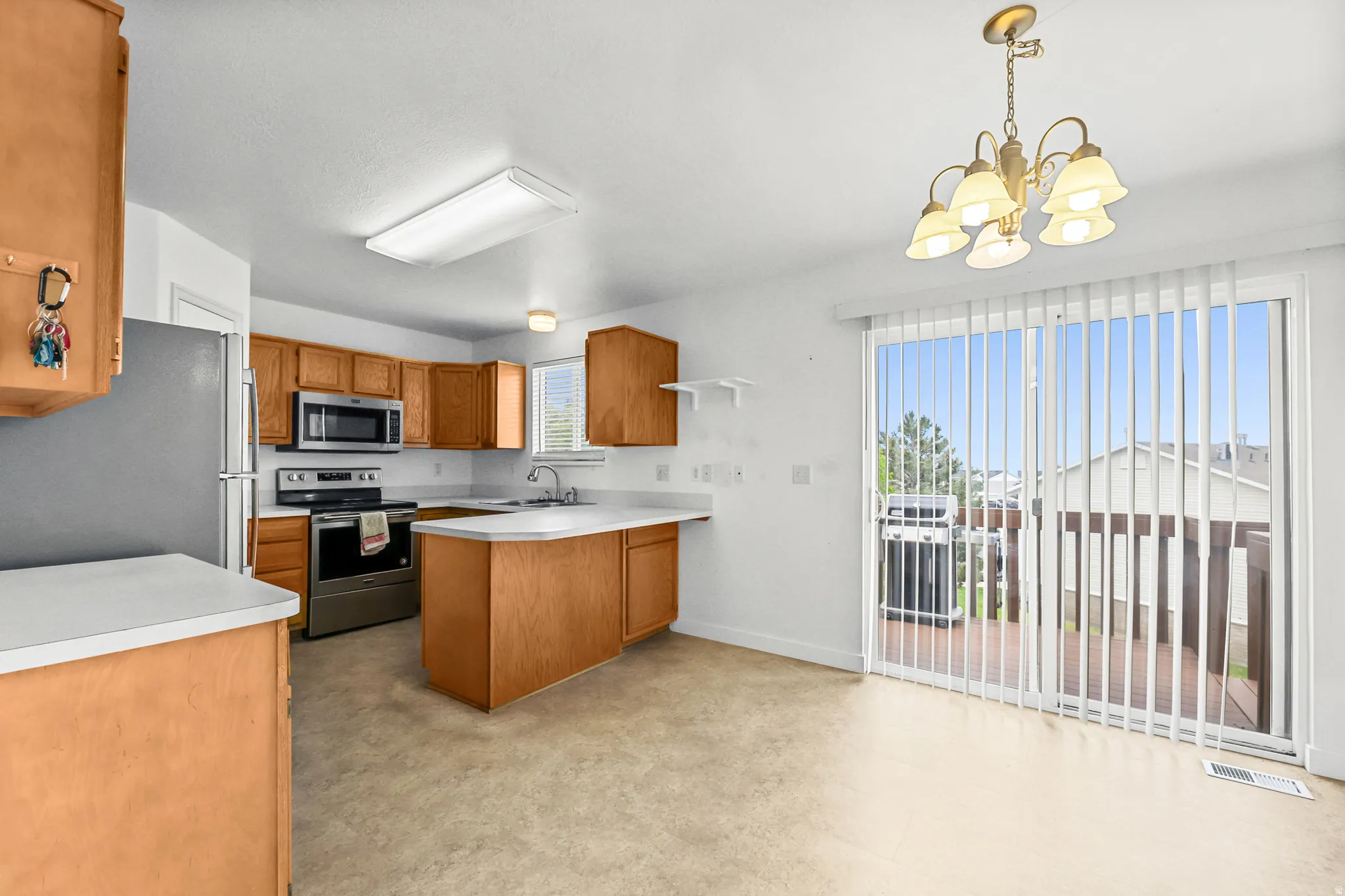 Full kitchen featuring wood cabinetry, stainless steel appliances, and an island with a sink