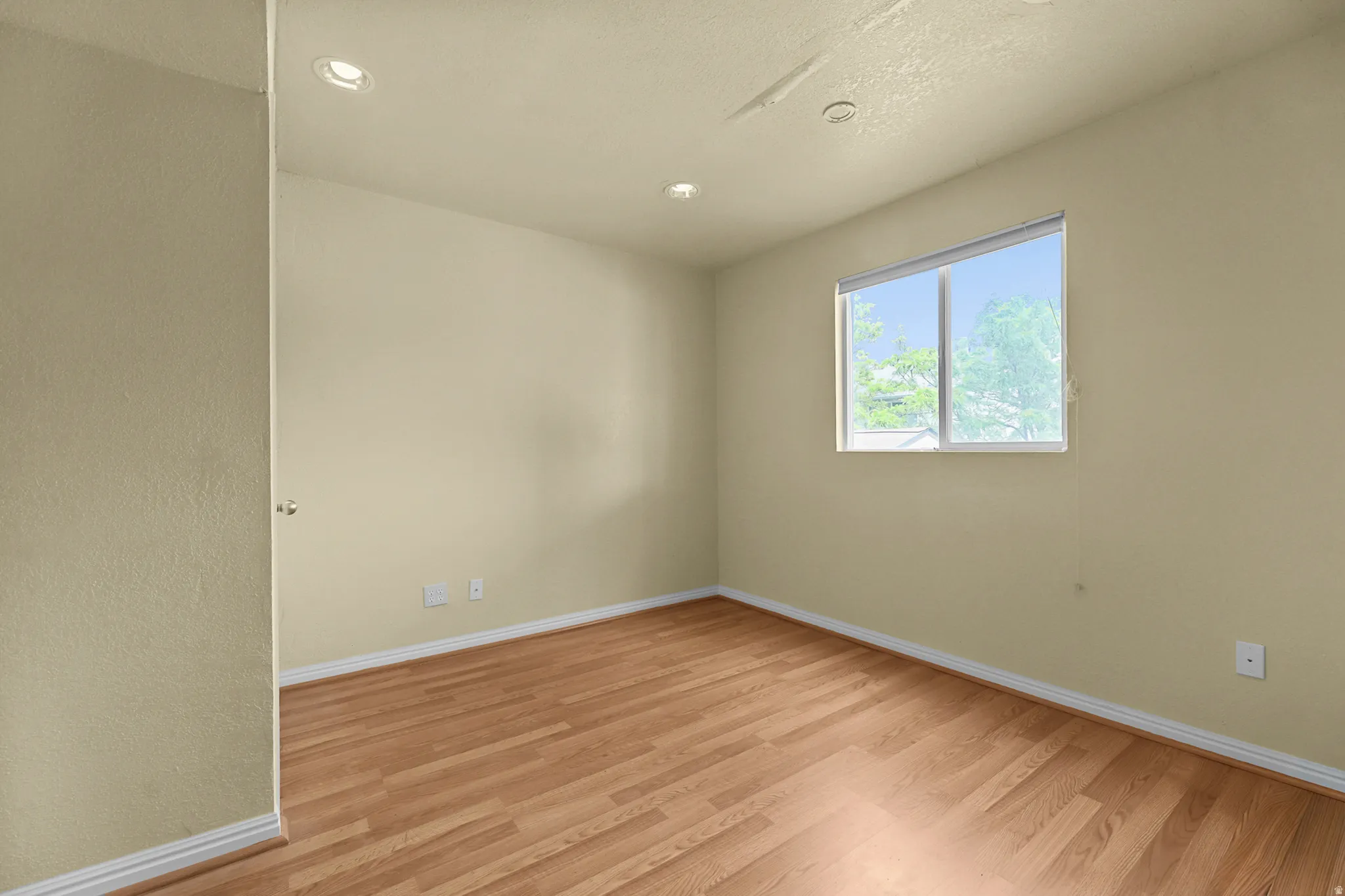 Spacious room featuring wood-finish flooring, recessed lighting, and a large window