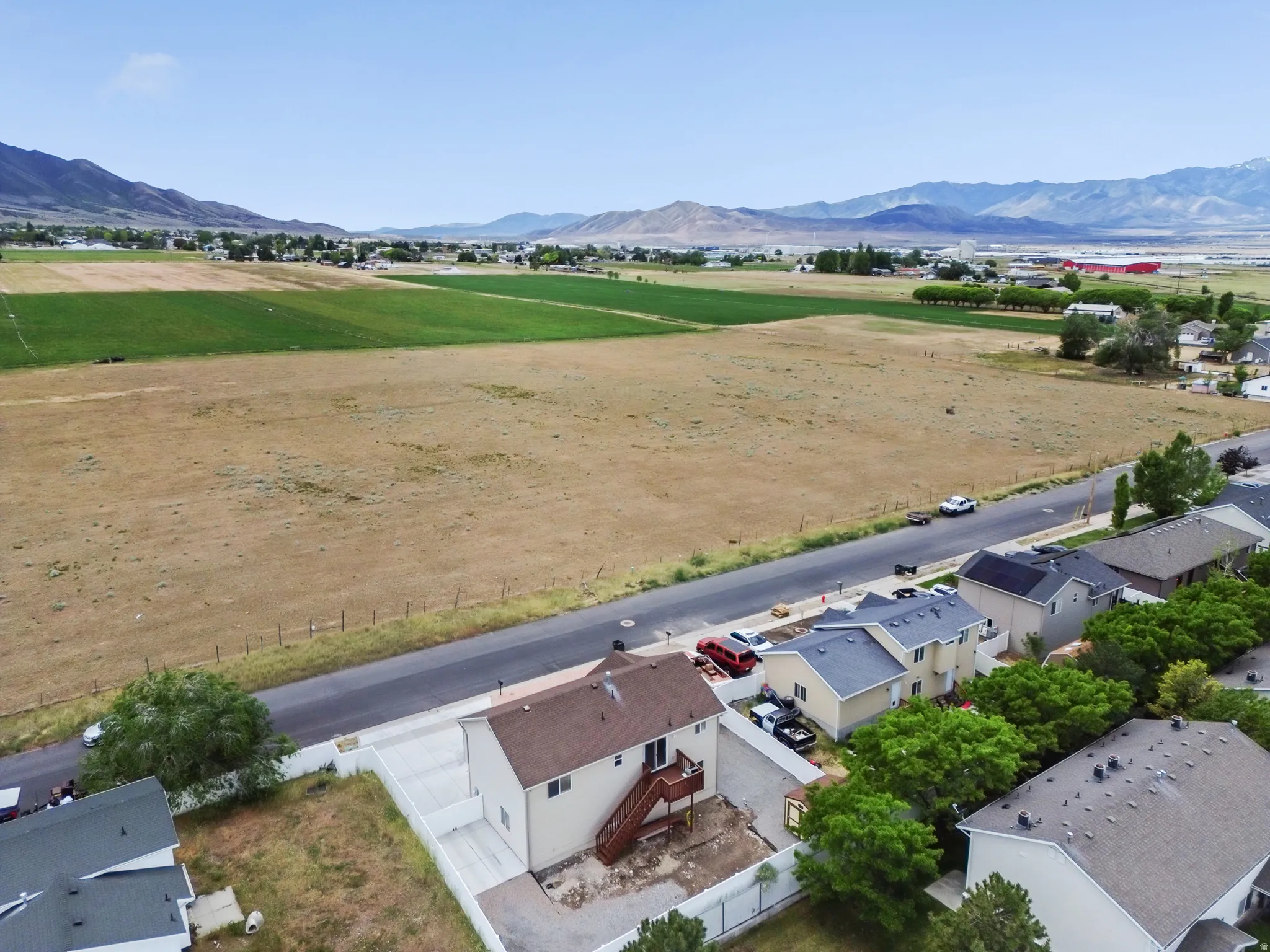 Aerial perspective showcasing a residential property with a brown shingle roof and light-colored siding