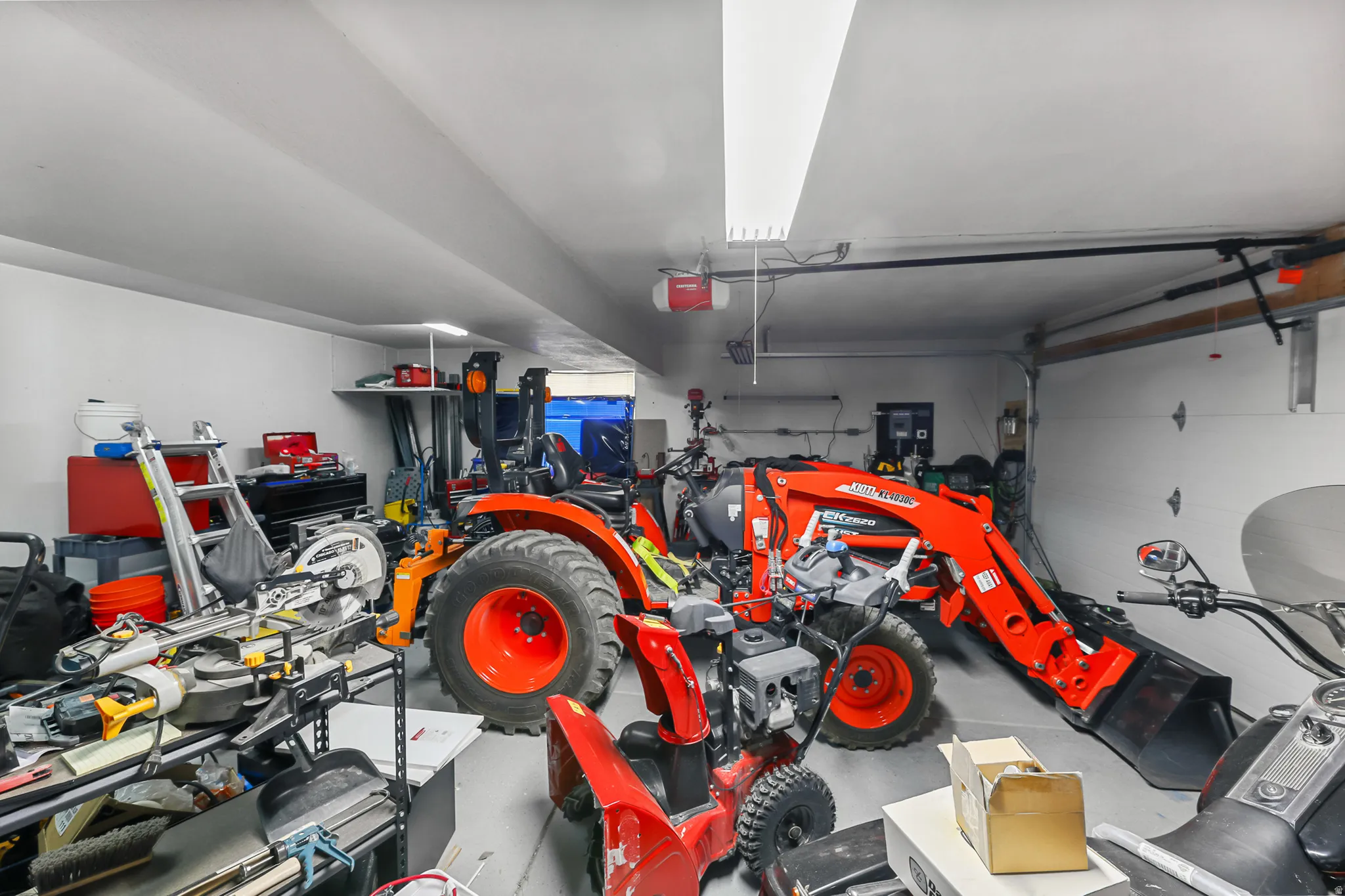 Spacious garage featuring a painted concrete floor, white walls, and bright overhead lighting