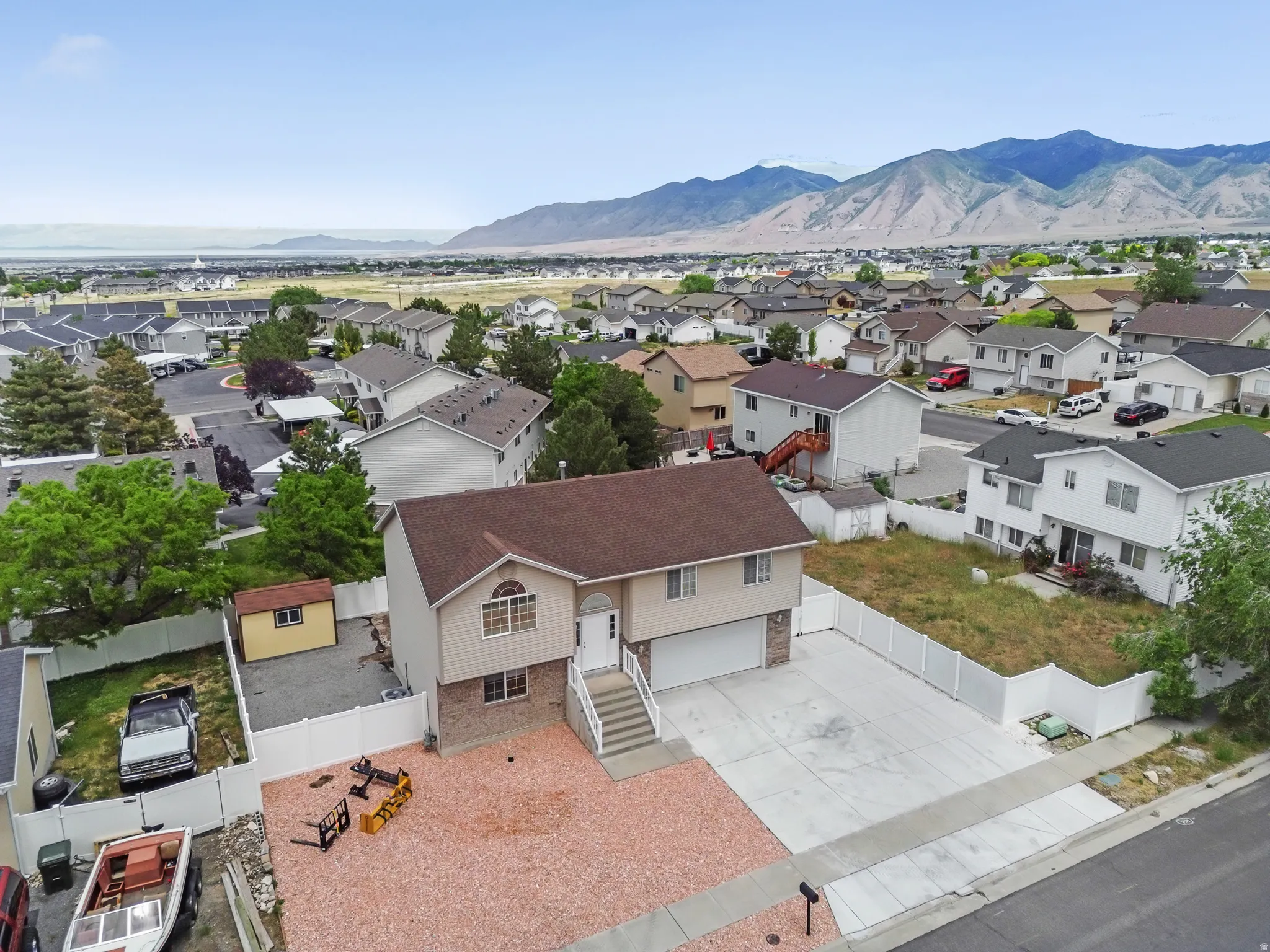 Split-level residence featuring a two-car garage, concrete driveway, and a gravel front yard