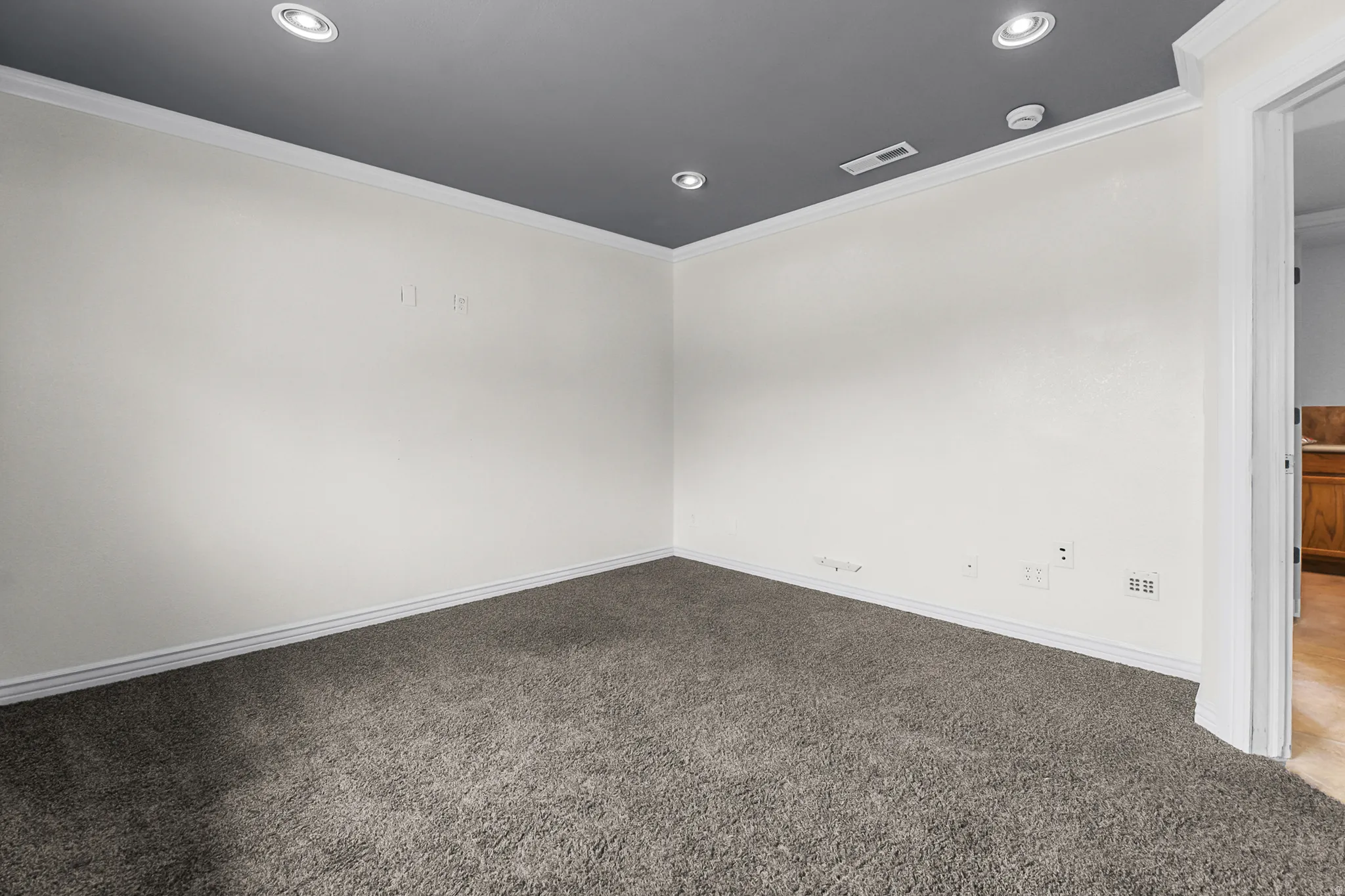Neutral-toned wall space with recessed lighting and crown molding