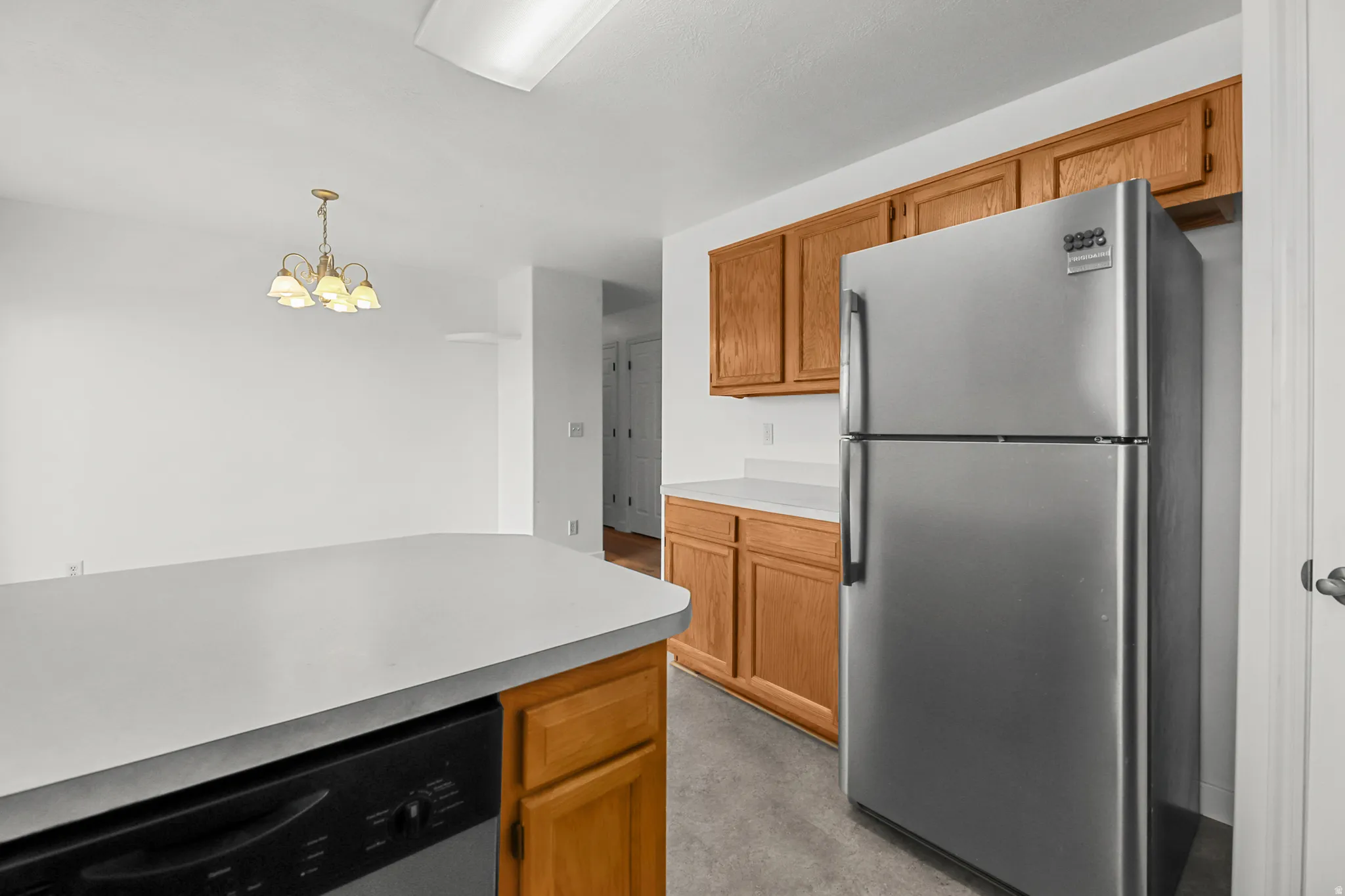 Kitchen with wood cabinetry, light-toned countertops, and a stainless steel refrigerator