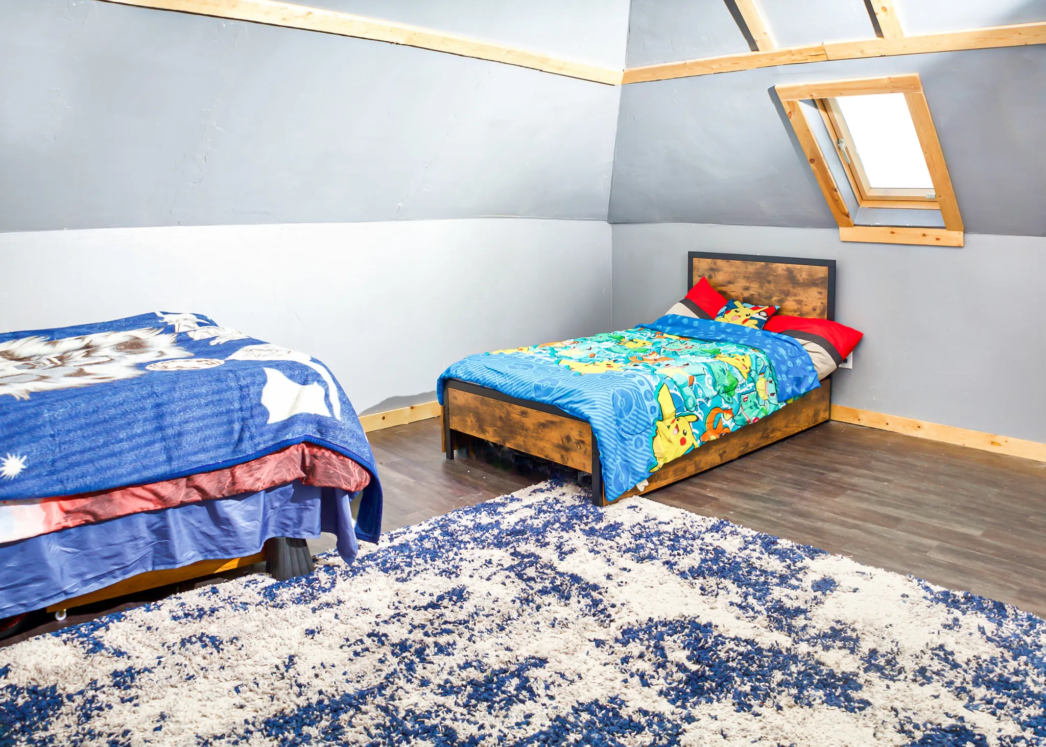 Sloped ceiling room featuring a skylight with natural wood trim, wood-finish flooring, and light gray walls