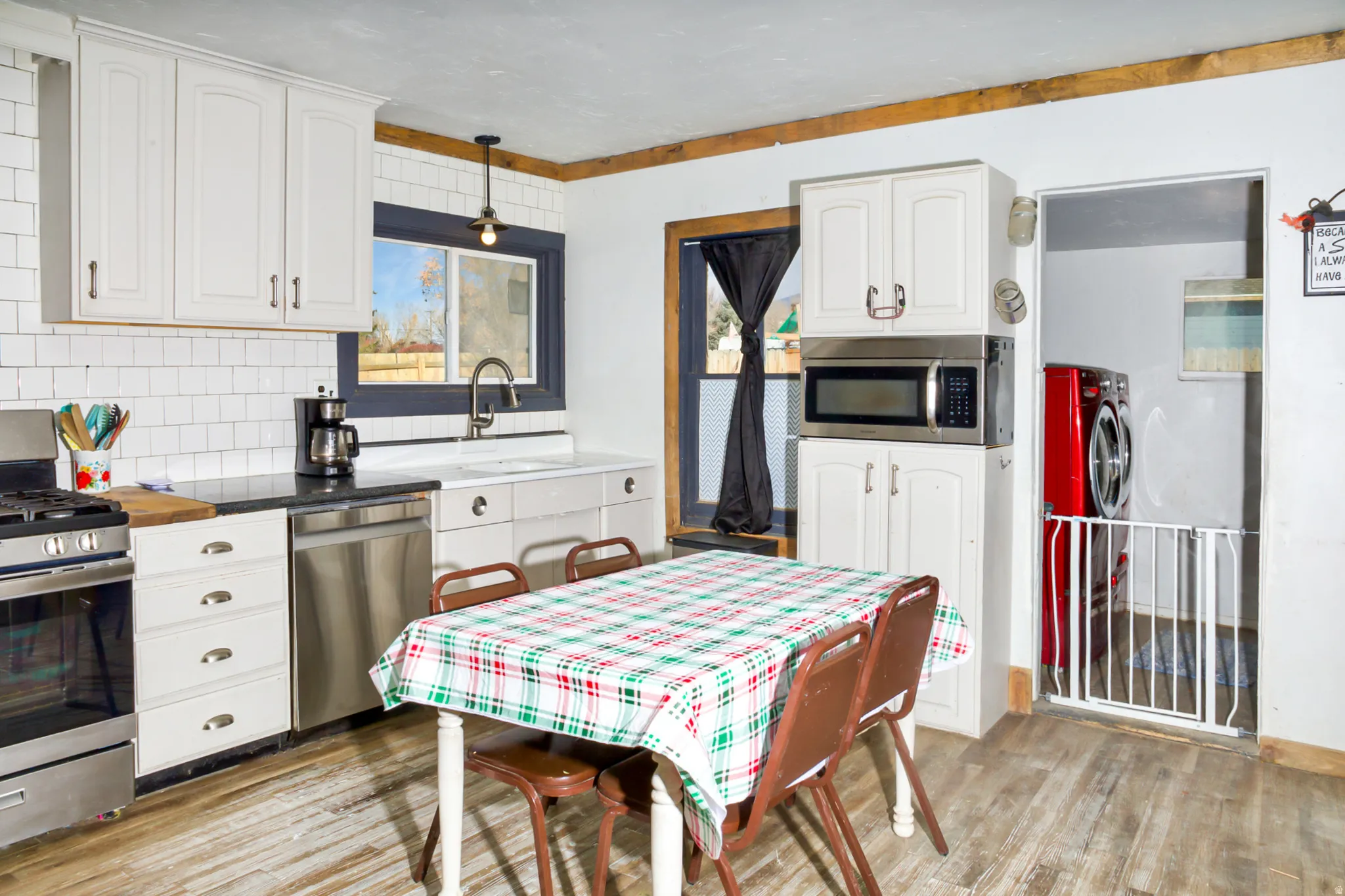 Kitchen featuring white cabinetry, subway tile backsplash, dark countertops, and wood-finish flooring