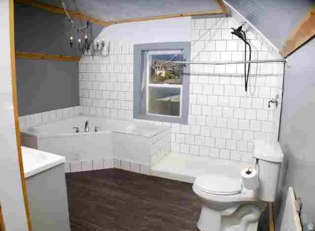 Bathroom featuring a corner soaking tub, a tiled shower enclosure, dark wood-finish flooring, a contemporary chandelier, and exposed wood beams