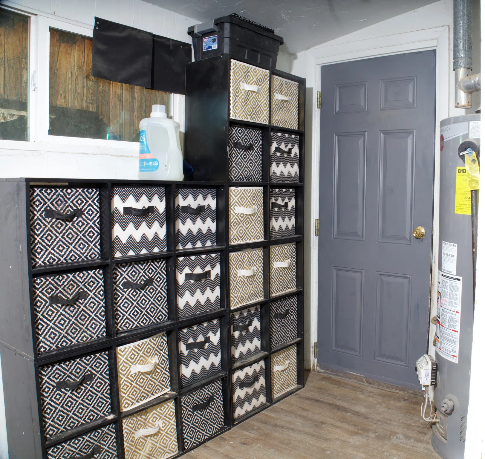 Utility room featuring a paneled door with a brass-finish knob, wood-finish flooring, a window, and a built-in water heater