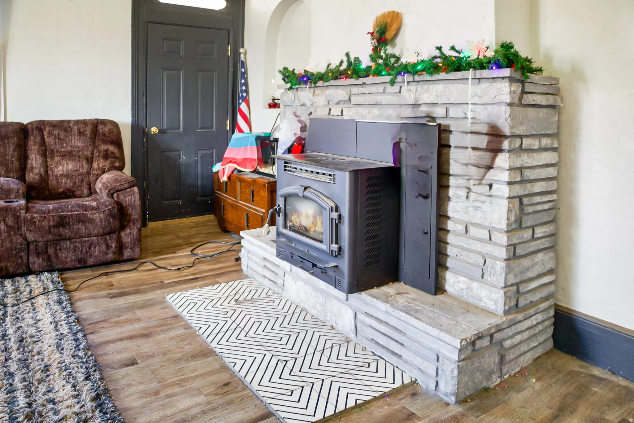 Stone-clad fireplace with a built-in stove insert, complemented by wood-finish flooring and white walls