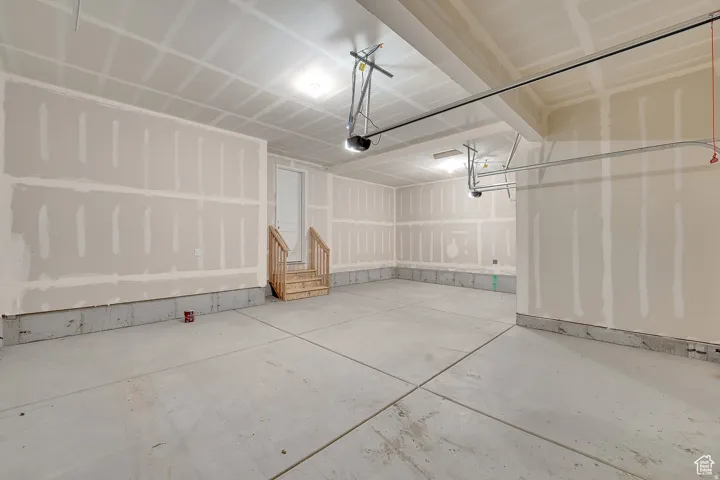 Spacious garage featuring a concrete floor, high ceilings, and exposed drywall
