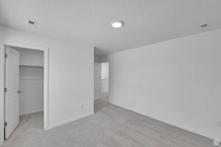 Spacious room with light gray carpeting and white painted walls