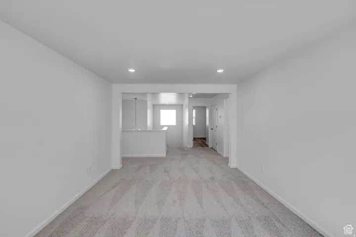 Spacious room with light neutral carpeting, recessed ceiling lighting, and a white interior door