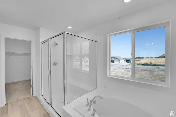 Contemporary bathroom featuring a glass-enclosed shower, a white soaking tub with polished chrome fixtures, and a large window