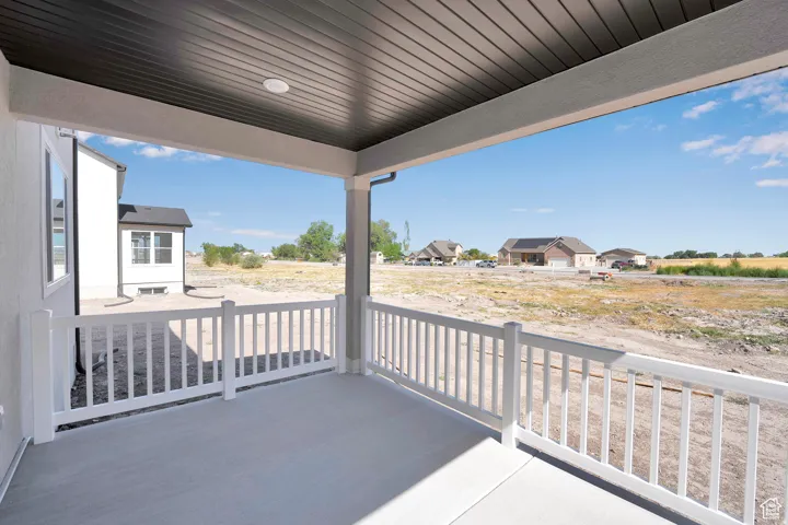 Covered concrete patio featuring white railing and a dark soffit ceiling with a recessed light fixture