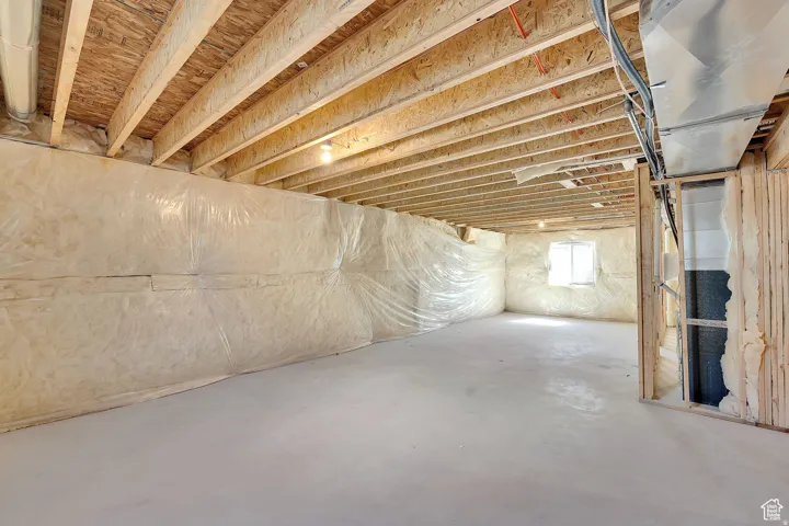 Unfinished basement with exposed ceiling joists and concrete flooring