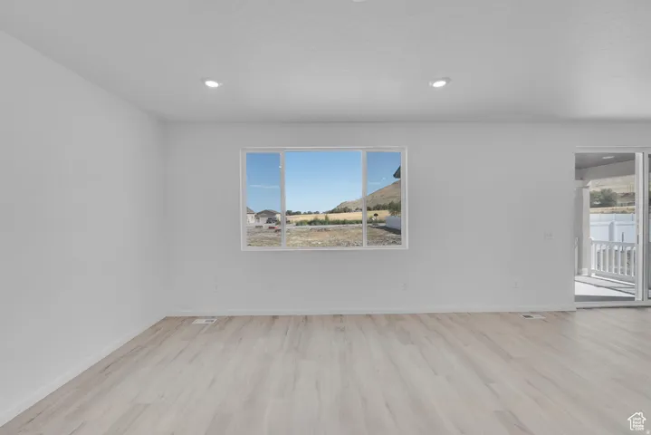 Spacious interior featuring light wood-finish flooring, recessed lighting, and a large window