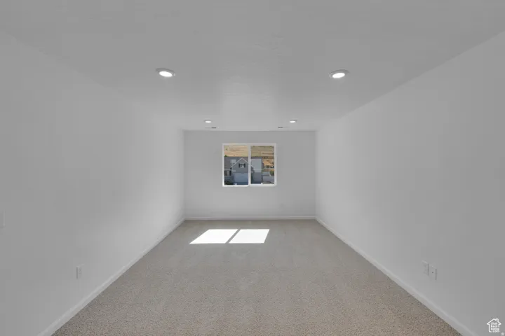 Carpeted room with recessed lighting and a window
