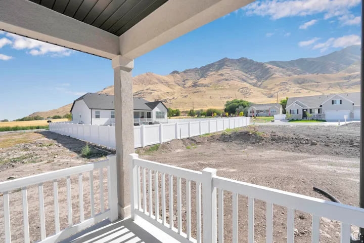 Covered porch featuring white railing system, neutral-toned column, and dark soffit, with a mountainous backdrop