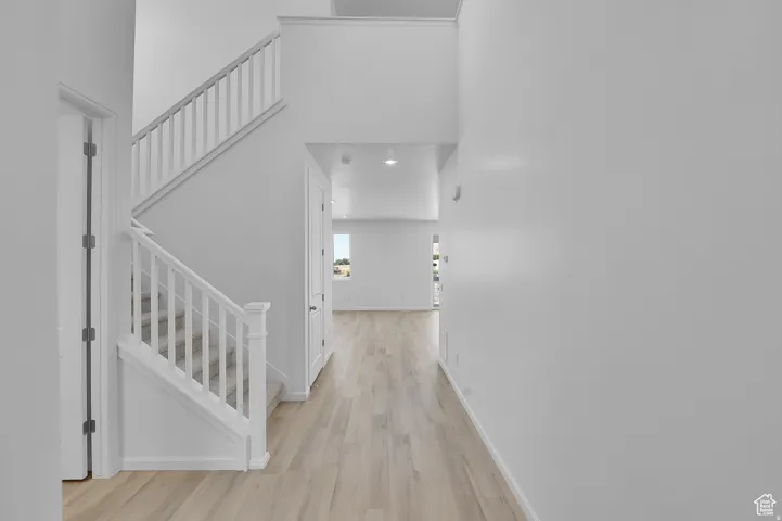 Entryway featuring a staircase with white balusters and carpeted treads, wood-finish flooring, recessed lighting, and a high ceiling