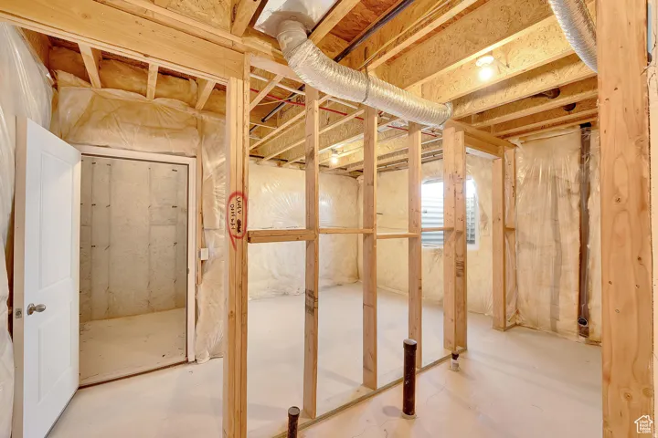 Unfinished basement presenting wood framing, exposed ductwork, concrete flooring, and an egress window