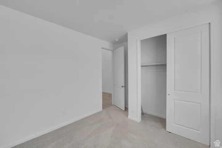 Neutral-toned carpeting and white walls in a room featuring a bi-fold closet with a hanging rod