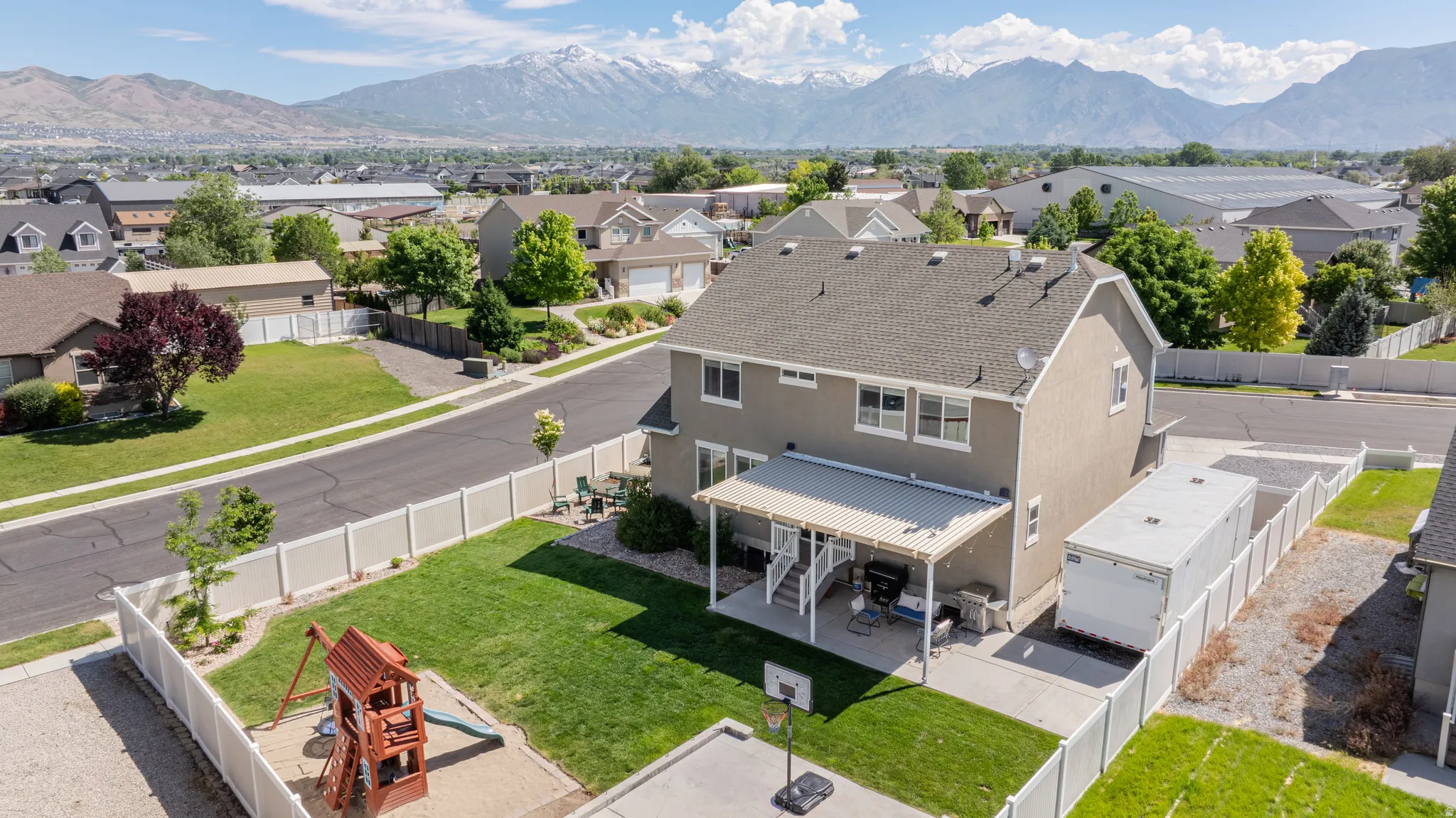 Expansive backyard featuring a manicured lawn, a covered patio, and a dedicated play area