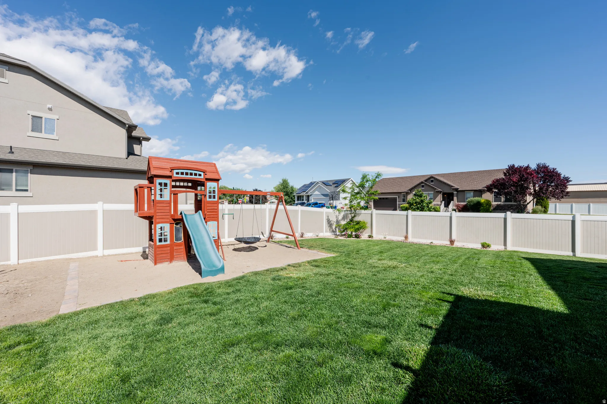 Expansive backyard featuring a manicured lawn and a sand play area