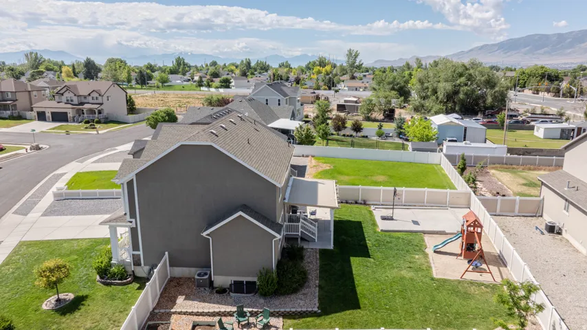 Expansive backyard featuring a large green lawn, concrete patio, and white privacy fencing