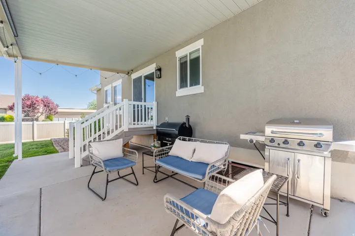 Expansive covered patio featuring a concrete surface, stucco exterior, and white railing system