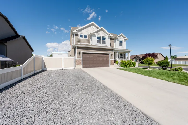 Two-story residence featuring a two-car garage, front porch, and a gravel side yard with a privacy fence and gate