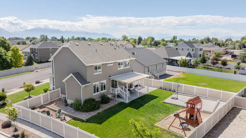 Expansive fenced backyard featuring a covered patio, a dedicated fire pit area, and a large green lawn