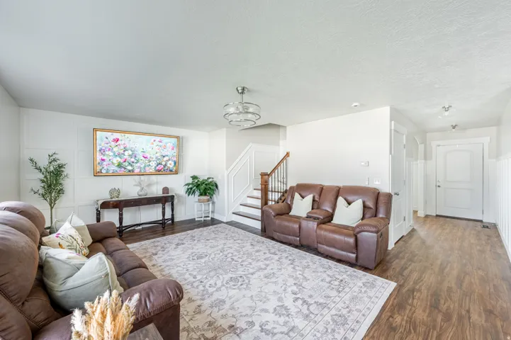 Spacious living area featuring paneling, wood-finish flooring, and a contemporary chandelier