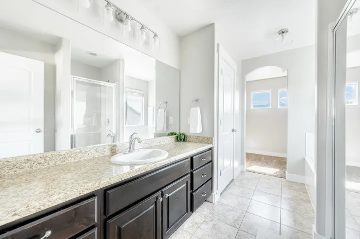 Spacious bathroom featuring a dark wood-finish vanity with an integrated sink, light-toned countertop, and a large wall-mounted mirror