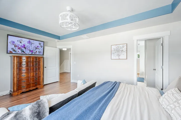 Recessed ceiling with blue trim, wood-finish flooring, white doors with modern hardware, and a decorative ceiling light fixture
