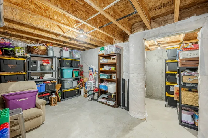 Unfinished basement space with exposed wood joists and concrete flooring