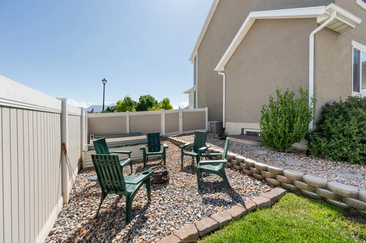 Outdoor gathering area featuring a gravel surface, stone retaining wall, and a built-in fire pit