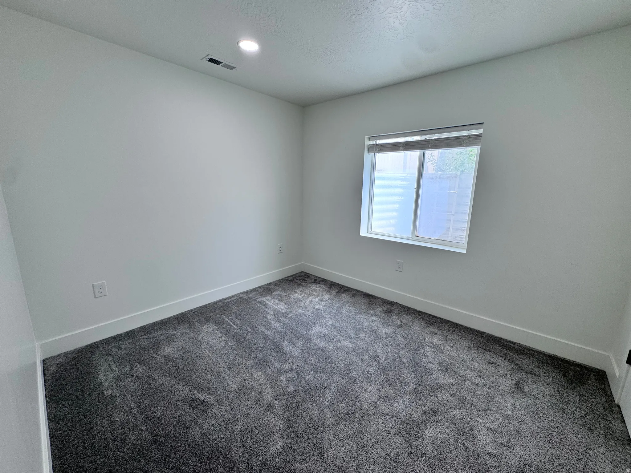Room featuring a neutral color palette, grey carpet flooring, white baseboards, and a window with blinds