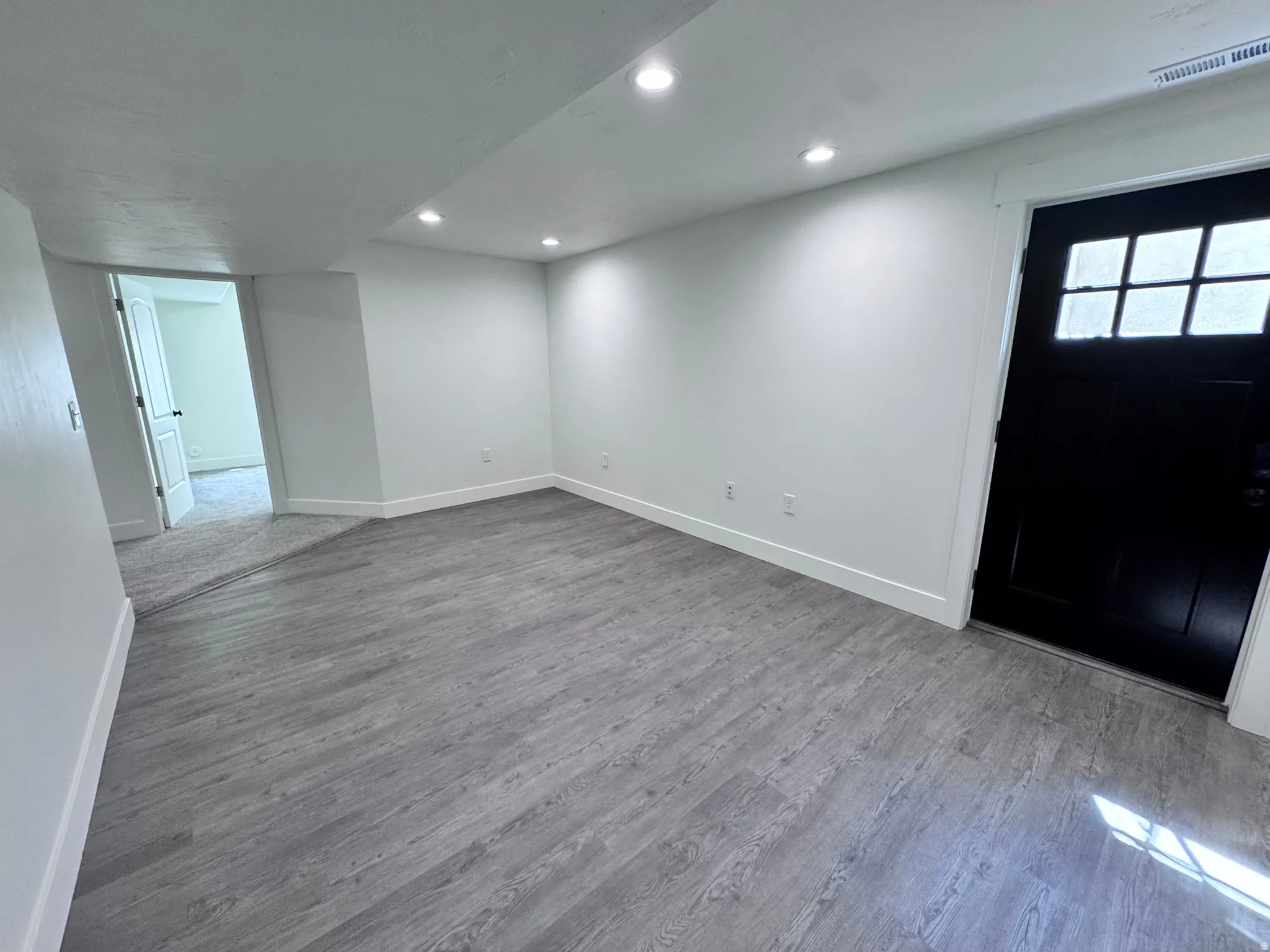 Spacious room featuring wood-finish flooring and recessed lighting