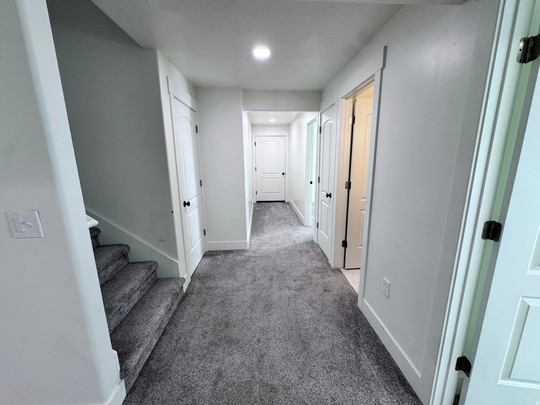 Hallway with textured gray carpeting, white walls, and recessed lighting