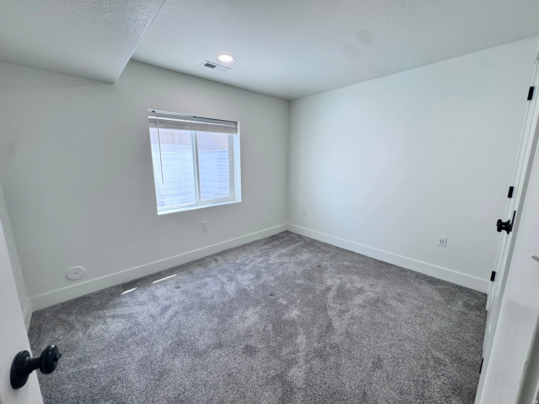 Room featuring plush gray carpeting, white walls, and a recessed ceiling light