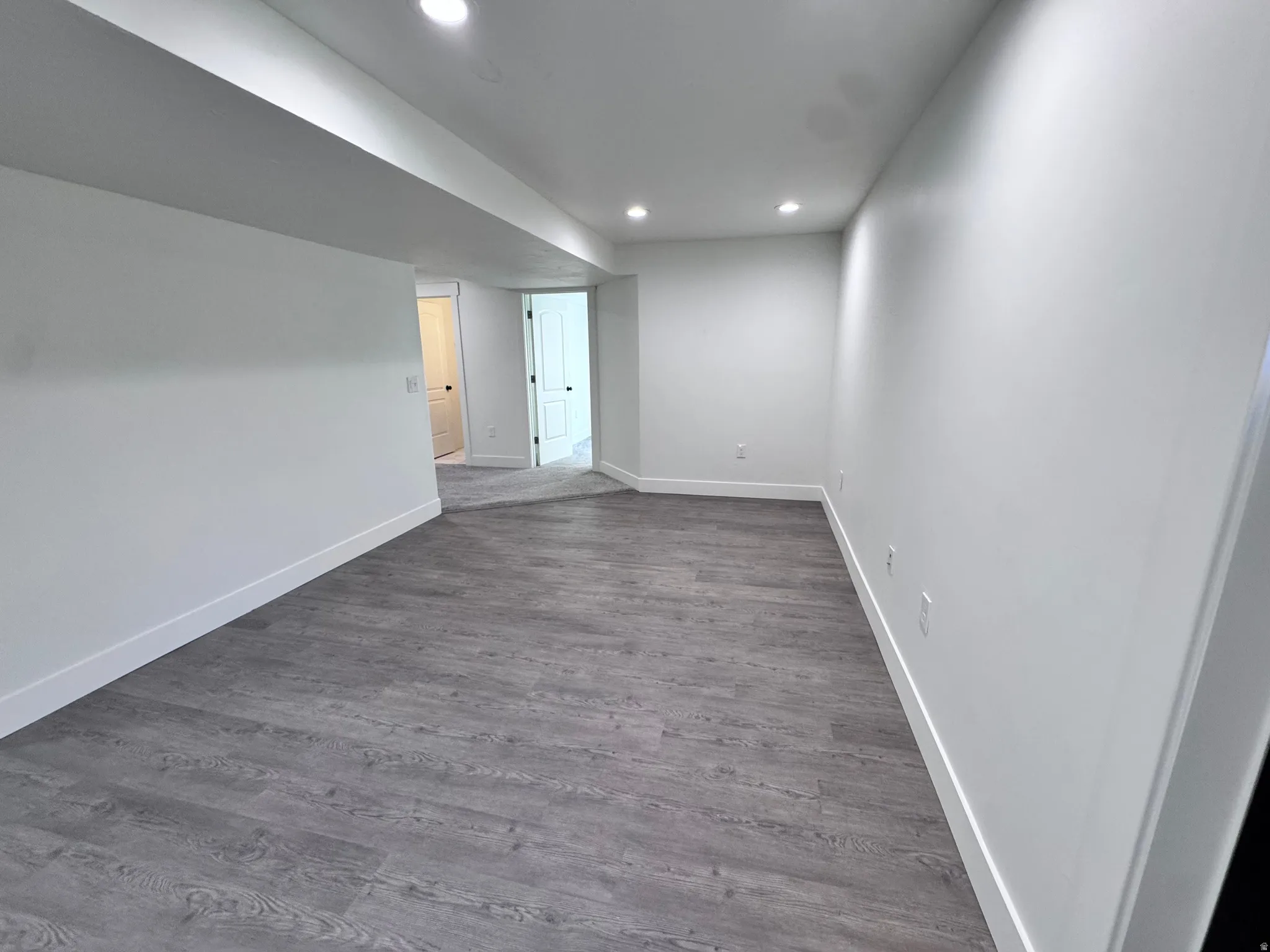 Spacious room featuring wood-finish flooring and recessed lighting