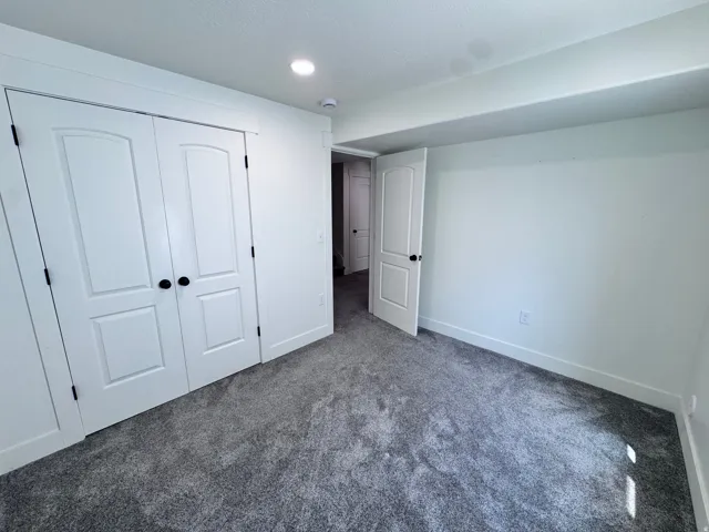 Carpeted room with white walls, recessed ceiling lighting, and crisp white trim