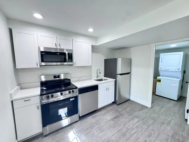 Modern kitchen featuring white shaker cabinetry, stainless steel appliances, white countertops with a matching backsplash, recessed lighting, and wood-finish flooring