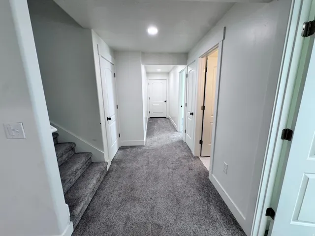 Hallway with textured gray carpeting, white walls, and recessed lighting
