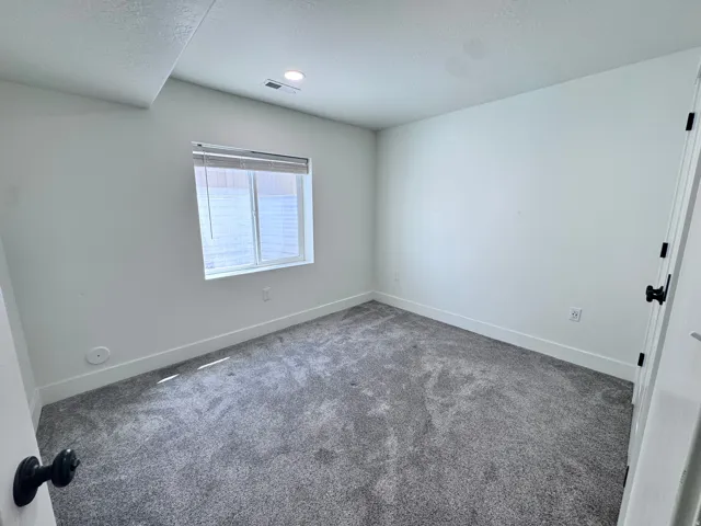 Room featuring plush gray carpeting, white walls, and a recessed ceiling light