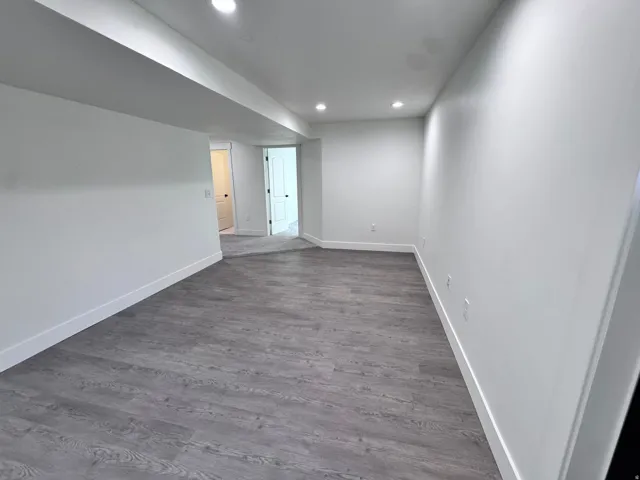 Spacious room featuring wood-finish flooring and recessed lighting